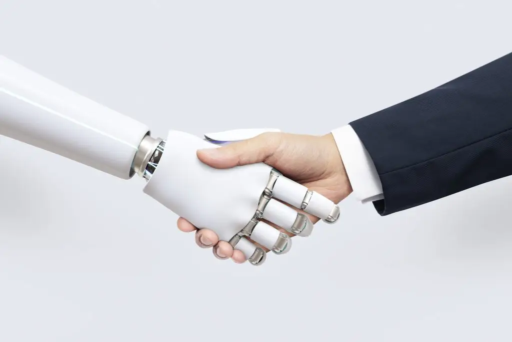 Human shaking hands with AI robot, symbolising AI-human collaboration and AI risk management