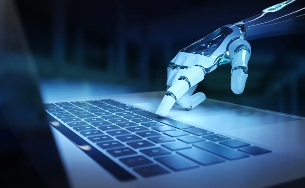 AI cyborg hand using a laptop representing modern cyber threats addressed in an ISO 27001 Implementation Guide